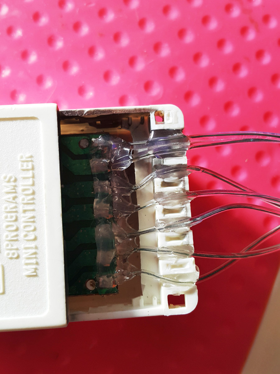 Applying hot glue inside one half of the plastic controller housing before closing it.