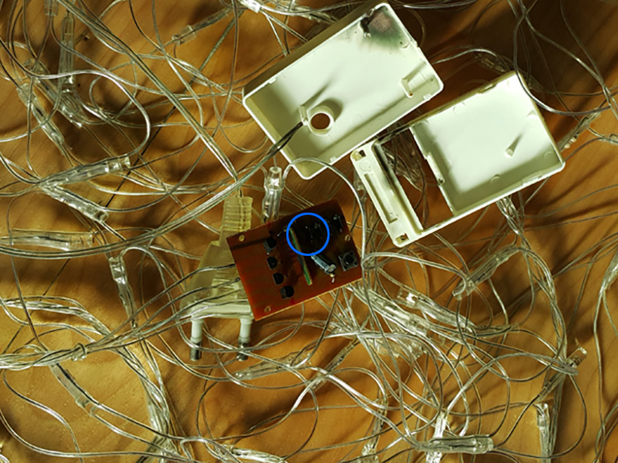 Close-up of the circuit board, focusing on the tiny blown diode circled in blue.