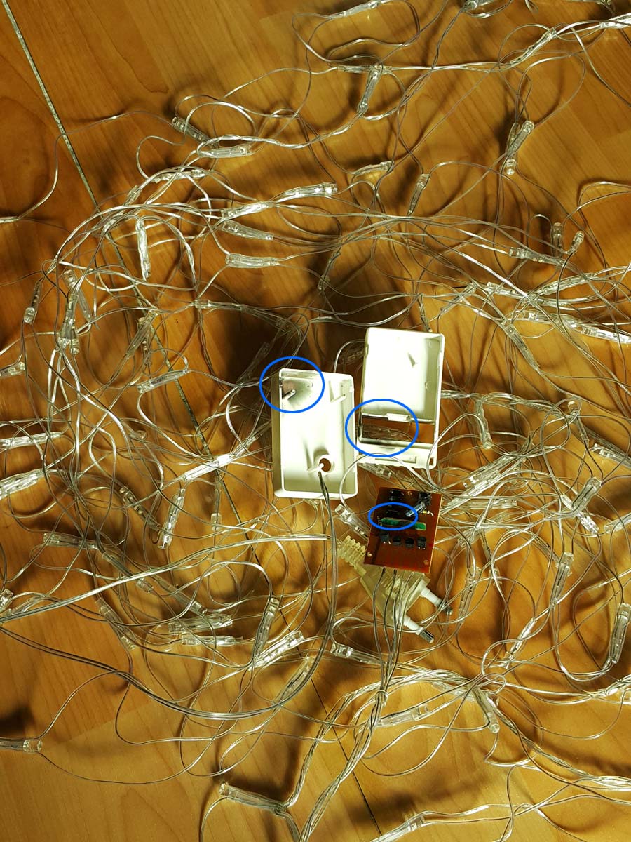 The disassembled Christmas light controller, showing various internal components and burn marks inside a blue circle.