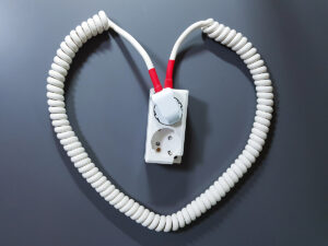 A white coiled extension cord neatly shaped into a heart.