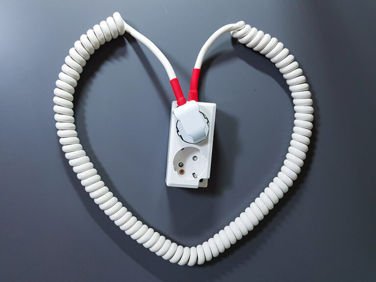 A white coiled extension cord neatly shaped into a heart.