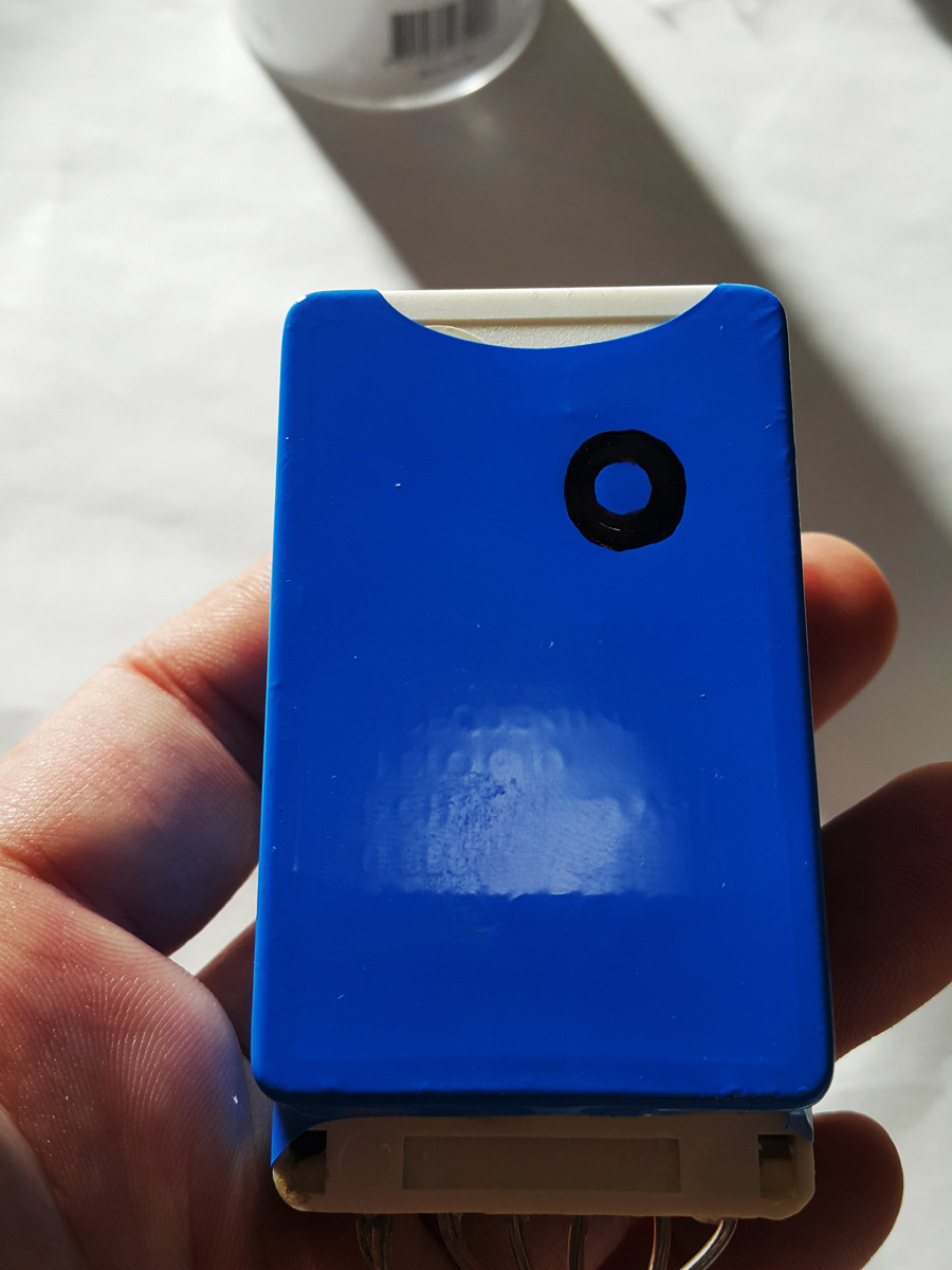The controller fully encased in blue shrink film, with the button's location marked with a pen.