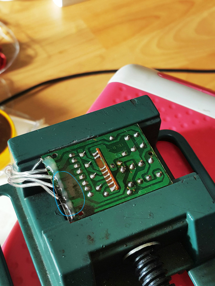 Close-up highlighting the original, poor-quality soldering of the wires onto the board.