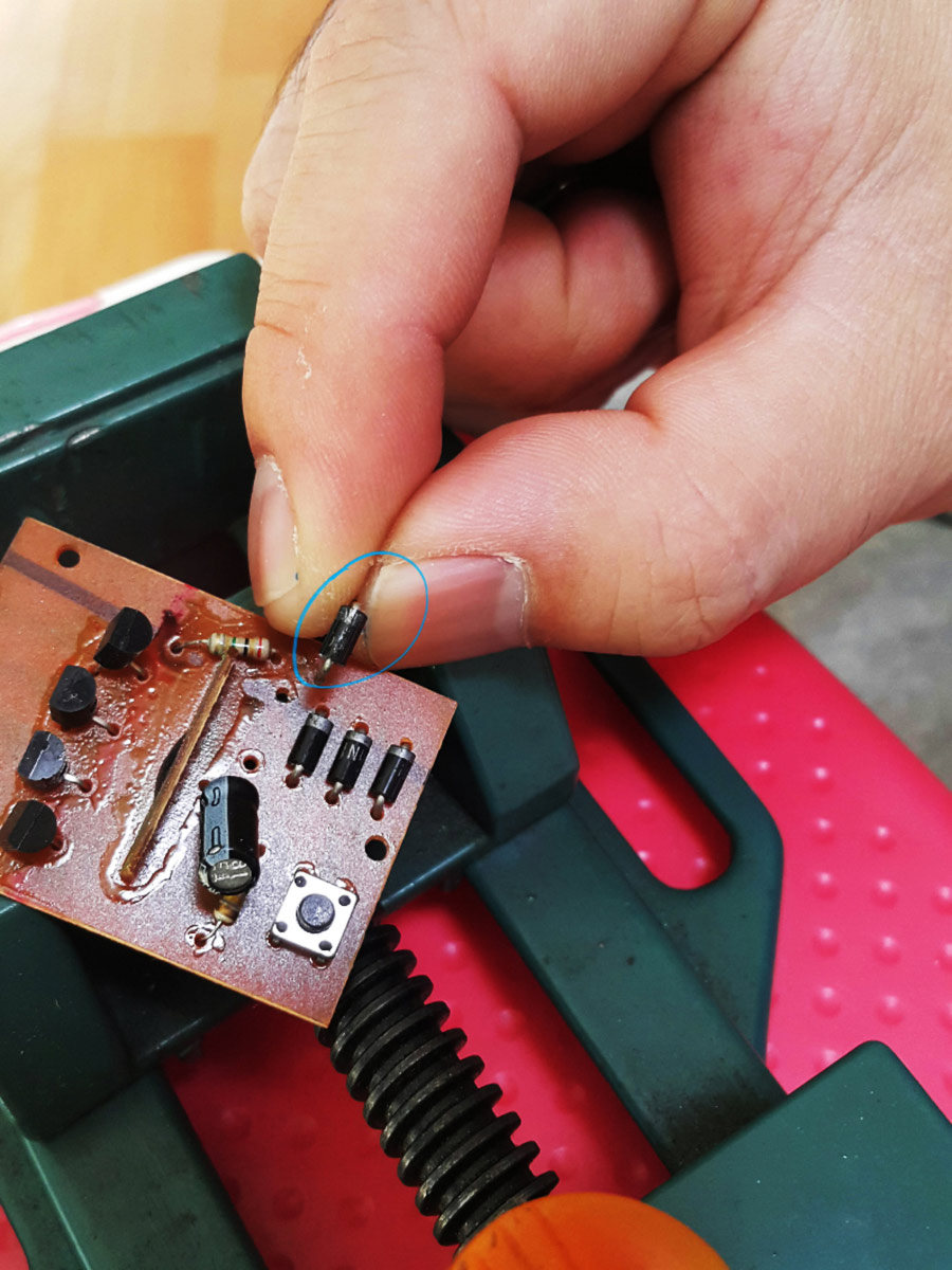 The tiny removed diode held between fingertips.