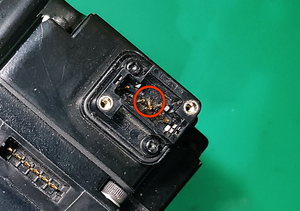 An extreme close-up view inside the connector, showing one single pin bent badly out of alignment.