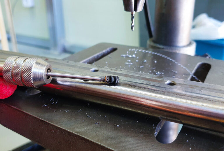 Close-up view of the broken bolt fragment successfully extracted and attached to the screw extractor.