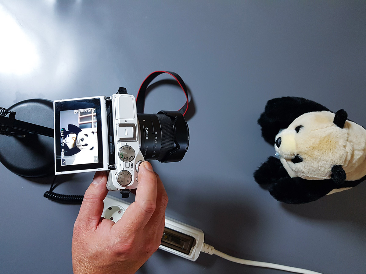 The EOS M3 is powered on and ready for a marathon recording session, connected to an external power source.