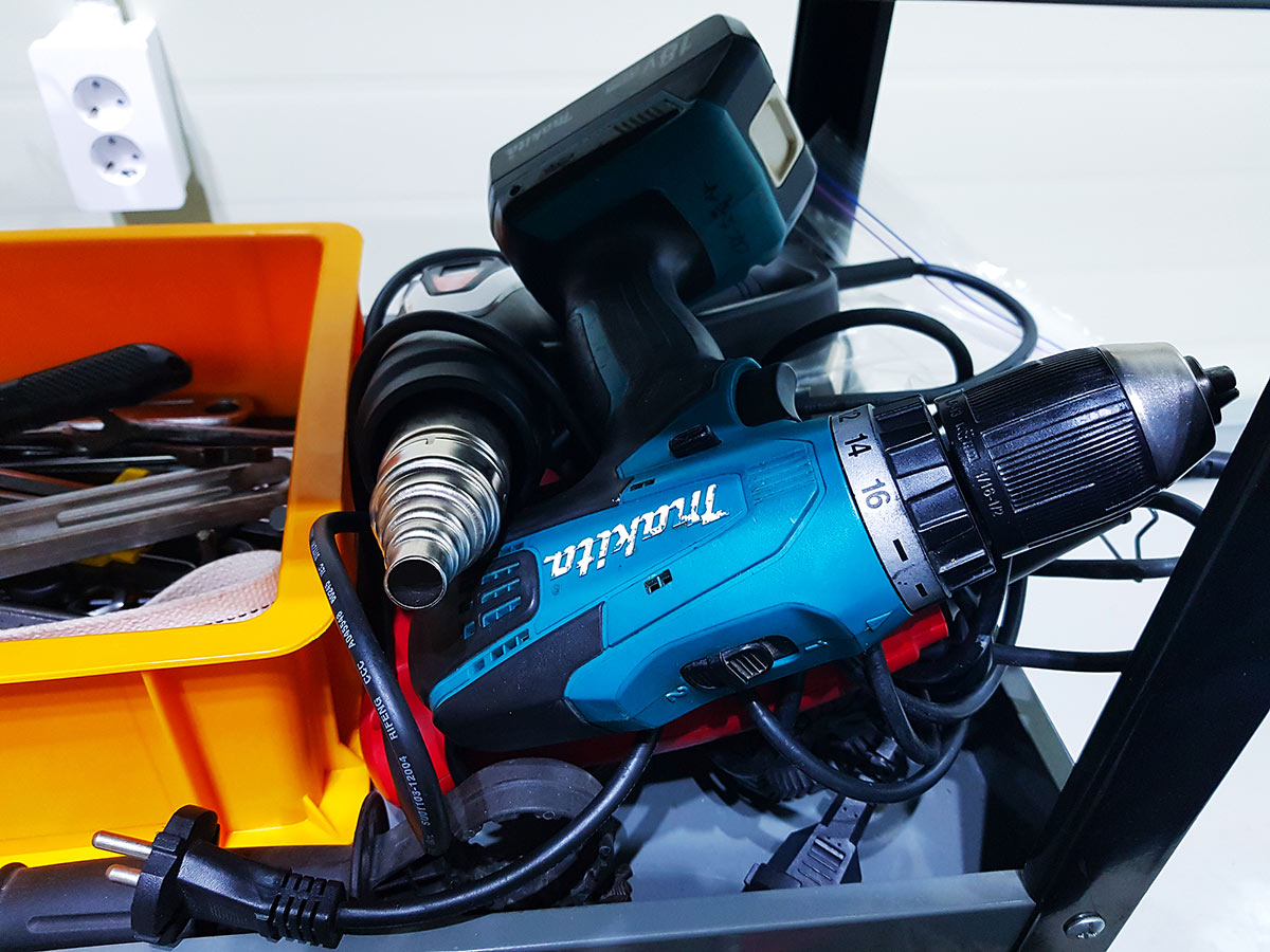 The messy tool cart trays cluttered with drills and tools.